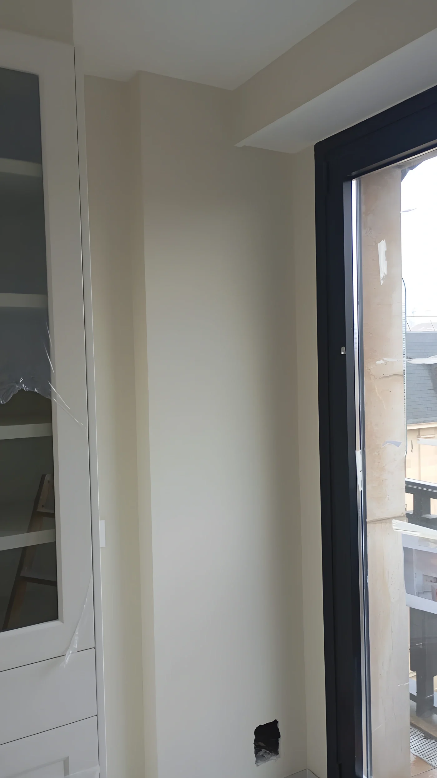 Salón recién pintado en tono crema junto a un ventanal con carpintería oscura